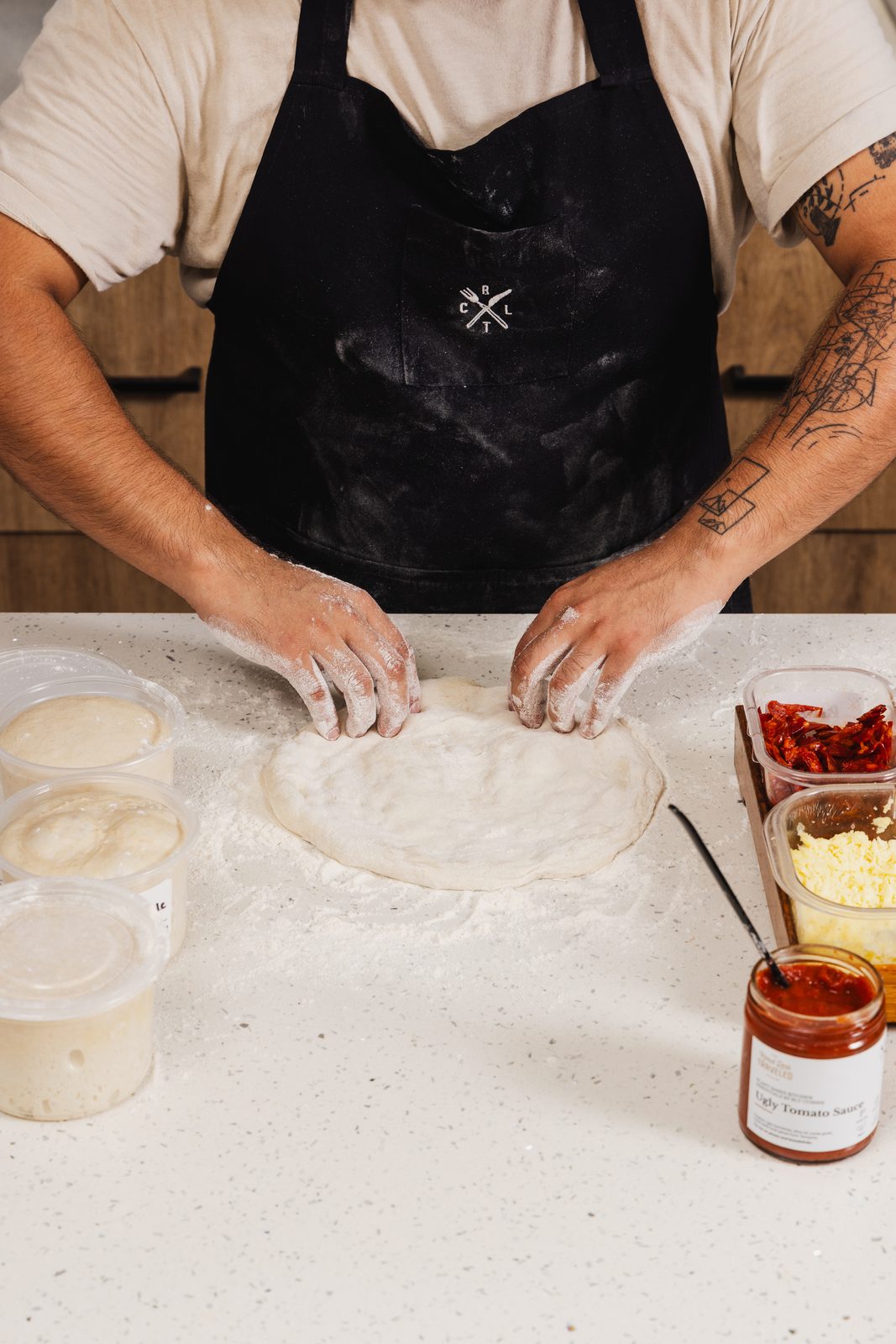 Hands working sourdough pizza dough on the bench