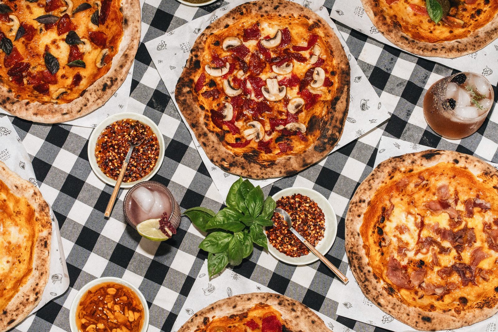 Six Holy Crust pizzas spread on a checkered cloth
