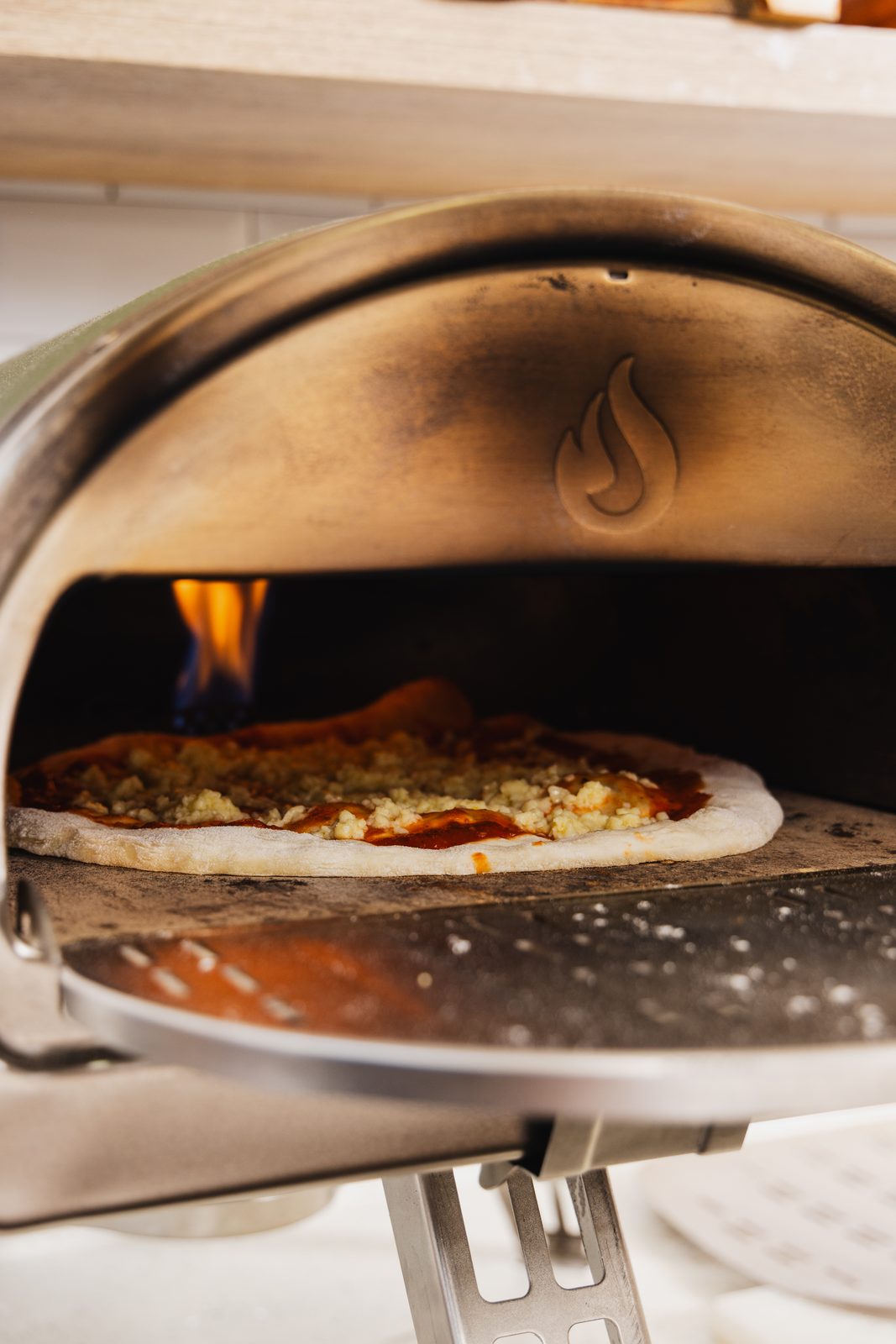 A pizza cooking in the flame of the stone oven